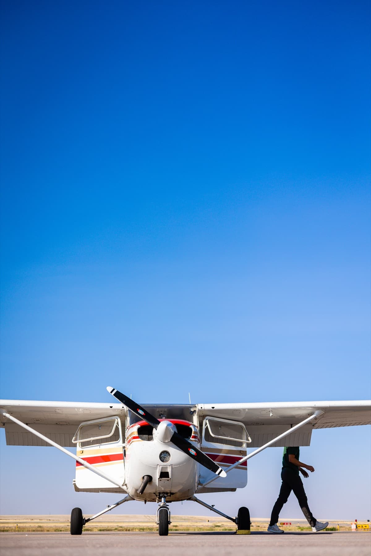 A small prop plane on the tarmac under a clear blue sky