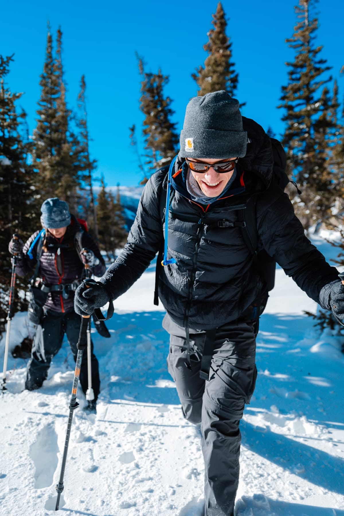 two hikers trudging through snow smiling