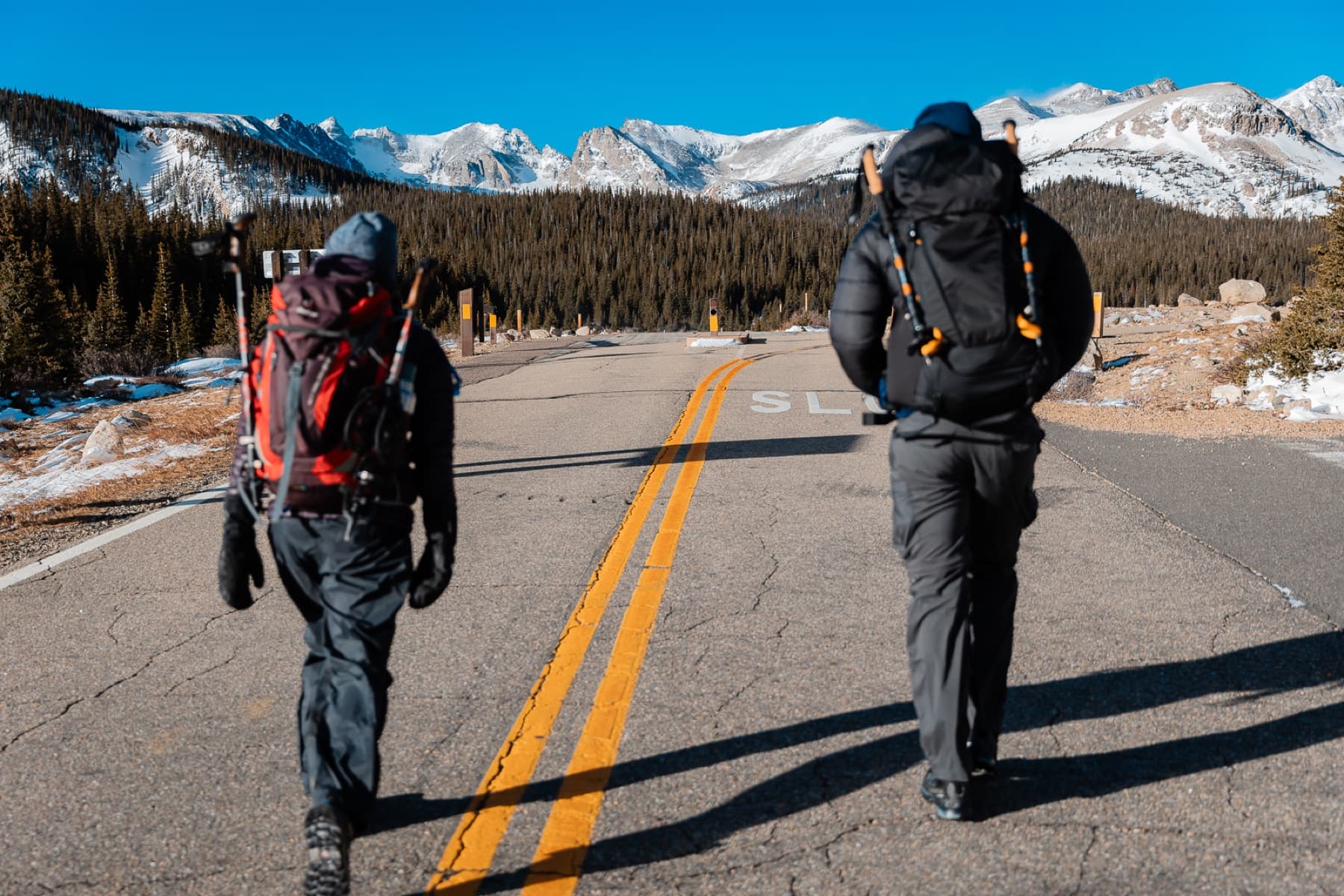 two hikers walking down colorado road in mountains