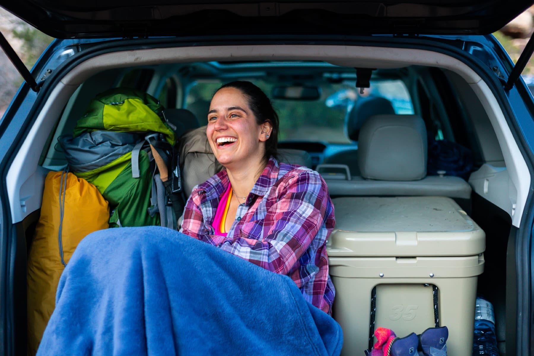 smiling camper in back hatch of subaru