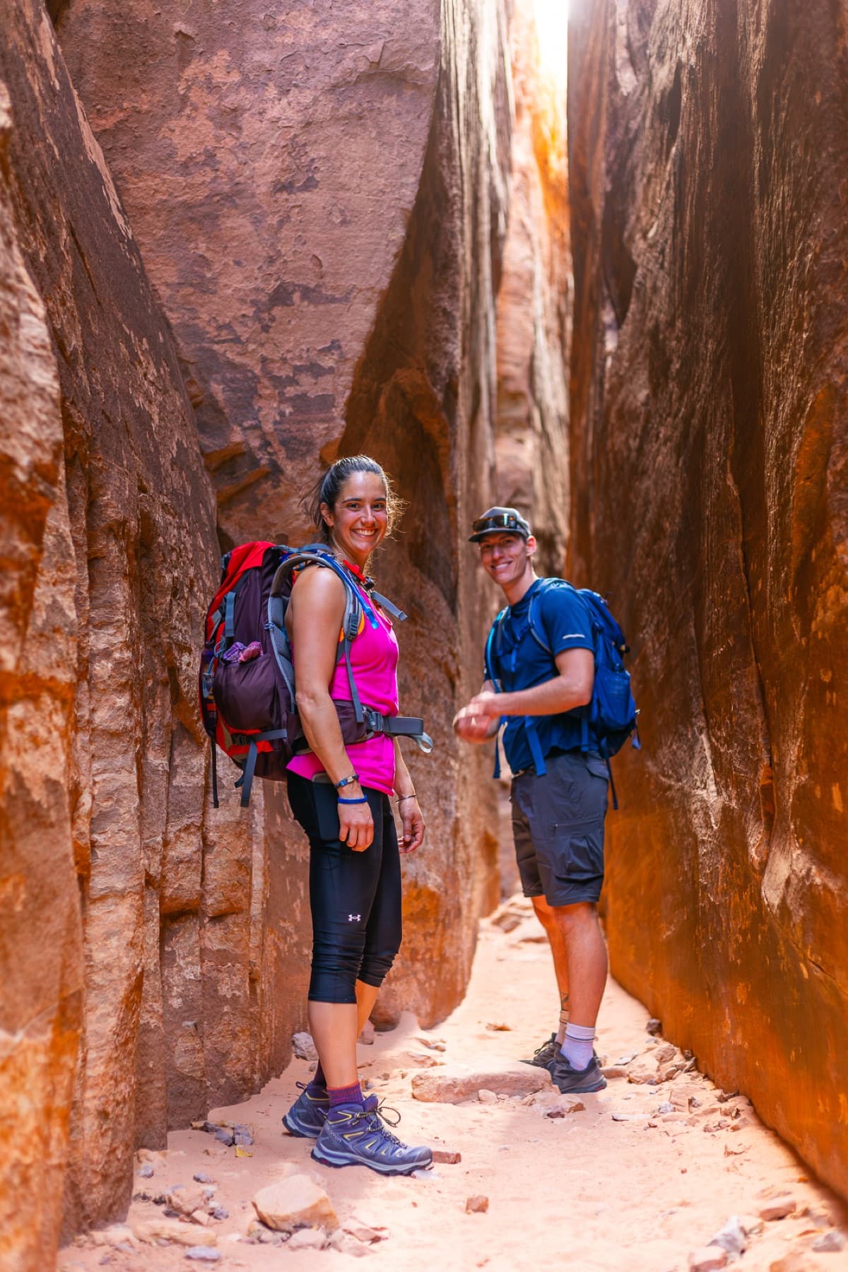 two smiling hikers in narrow slot canyon utah