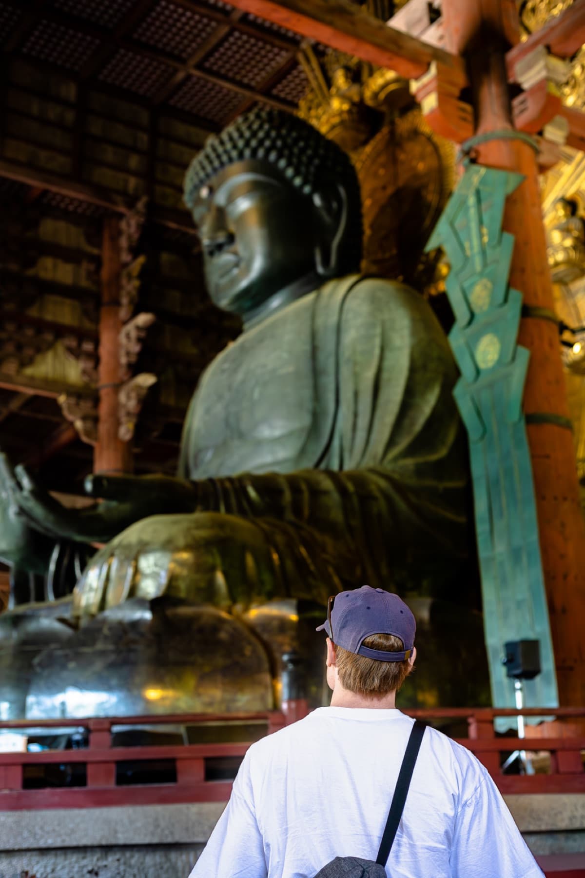young man looking up at buddha statue japan