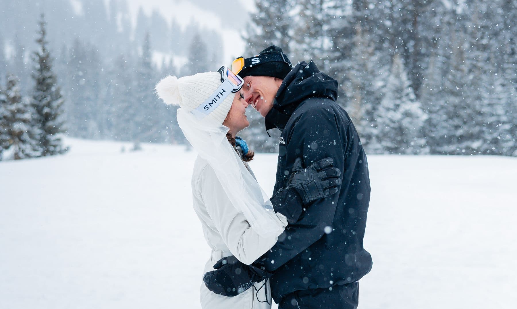 A couple kissing in falling snow at their Colorado ski elopement