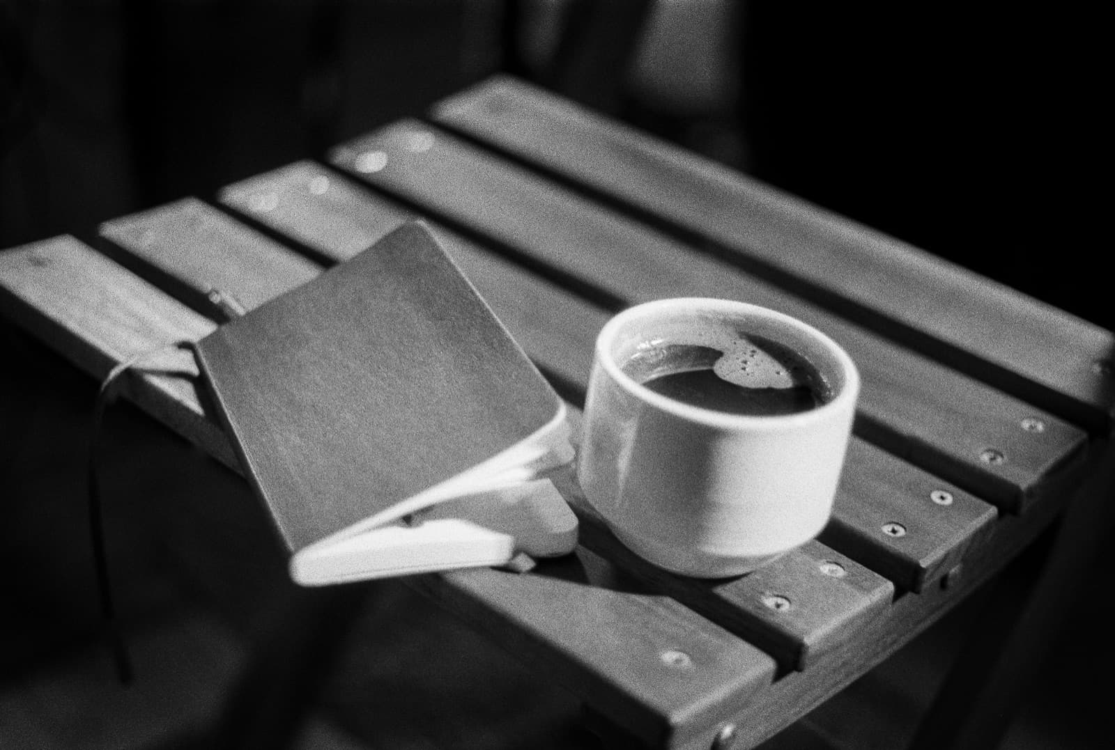 A journal and coffee on a table, black and white