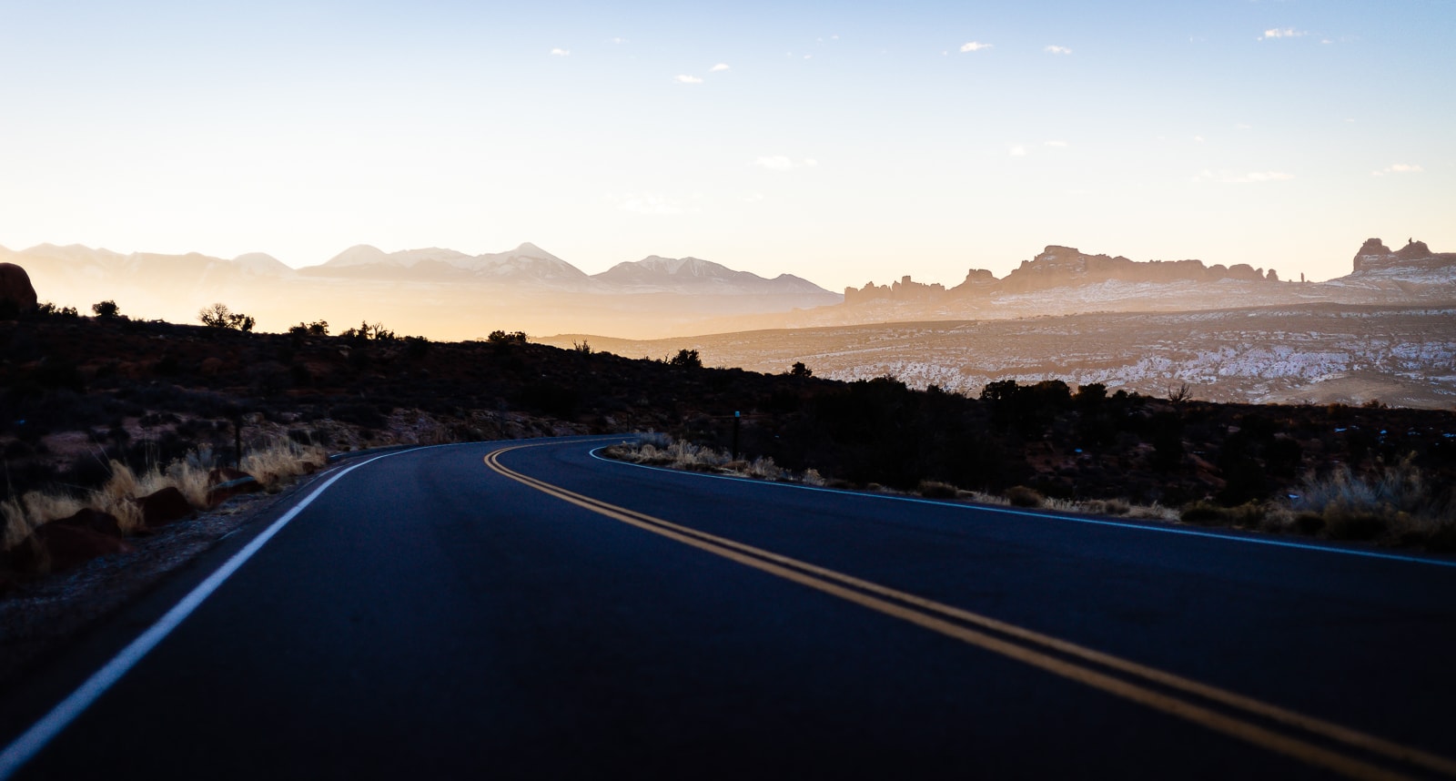A road winding through Arches National Park at sunrise